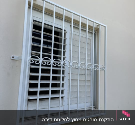 סורג מתכת לבן על חלון עם תריסים